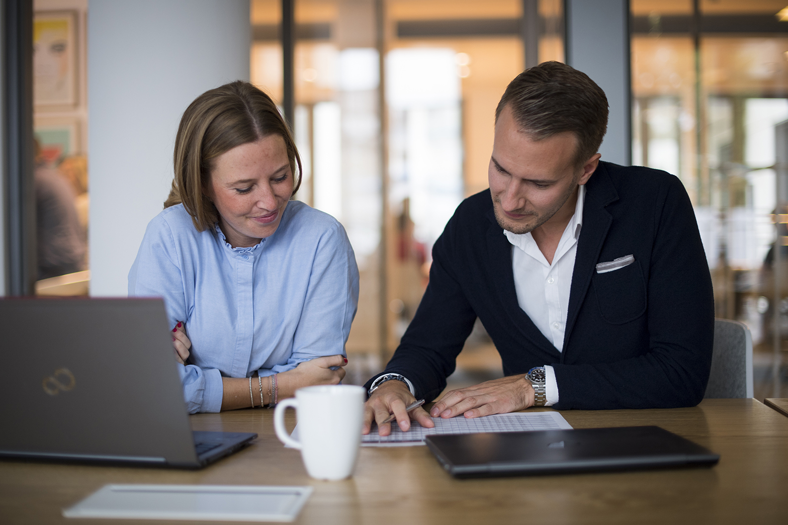 Eine Frau und ein Mann sitzen am Schreibtisch mit Laptop und Unterlagen