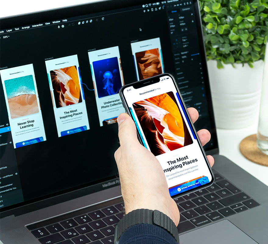 Ein Laptop auf dem eine Website geöffnet ist und ein Handy, auf dem eine App geöffnet ist, die denselben Inhalt wie auf der Website in mobiler Version zeigt.