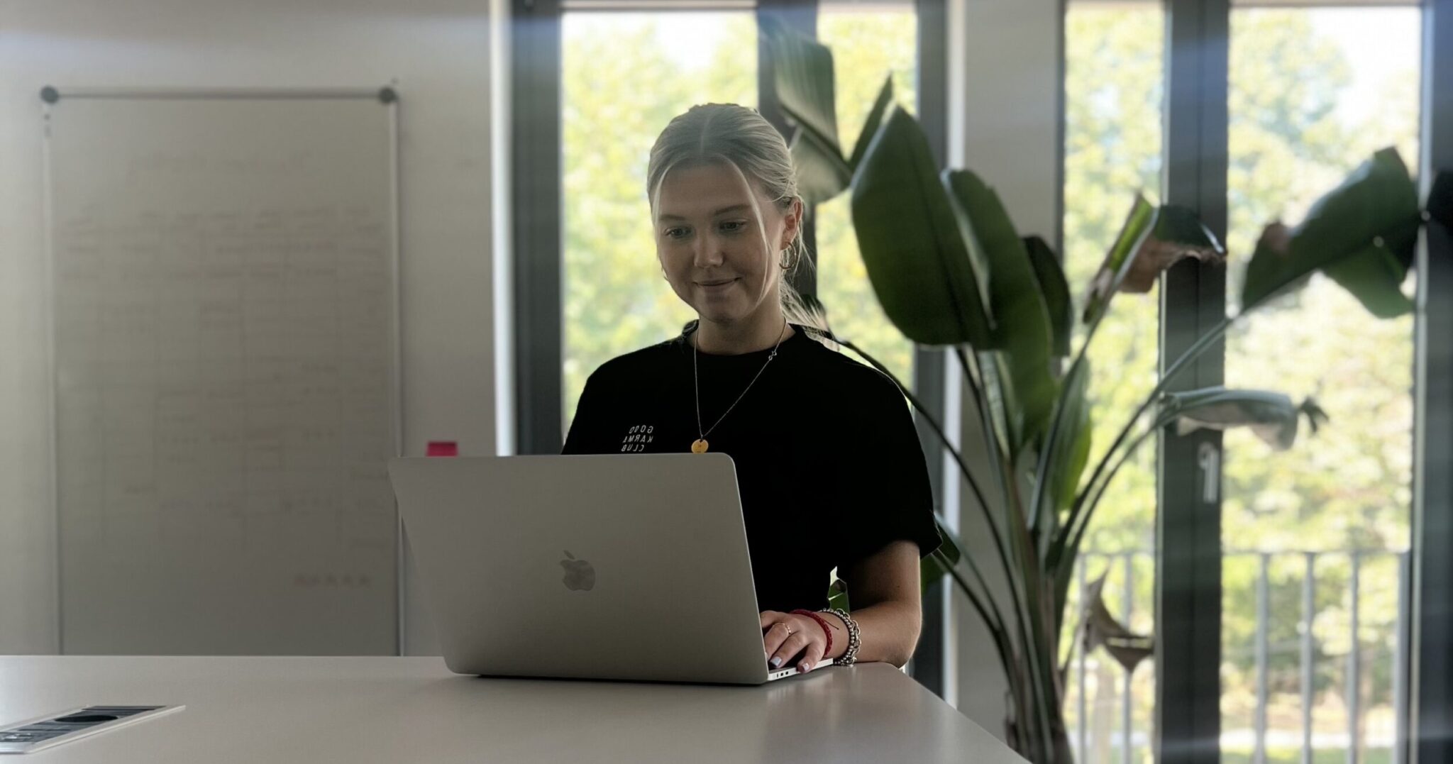 Julina sitzt am Schreibtisch im Büro und arbeitet am Laptop.