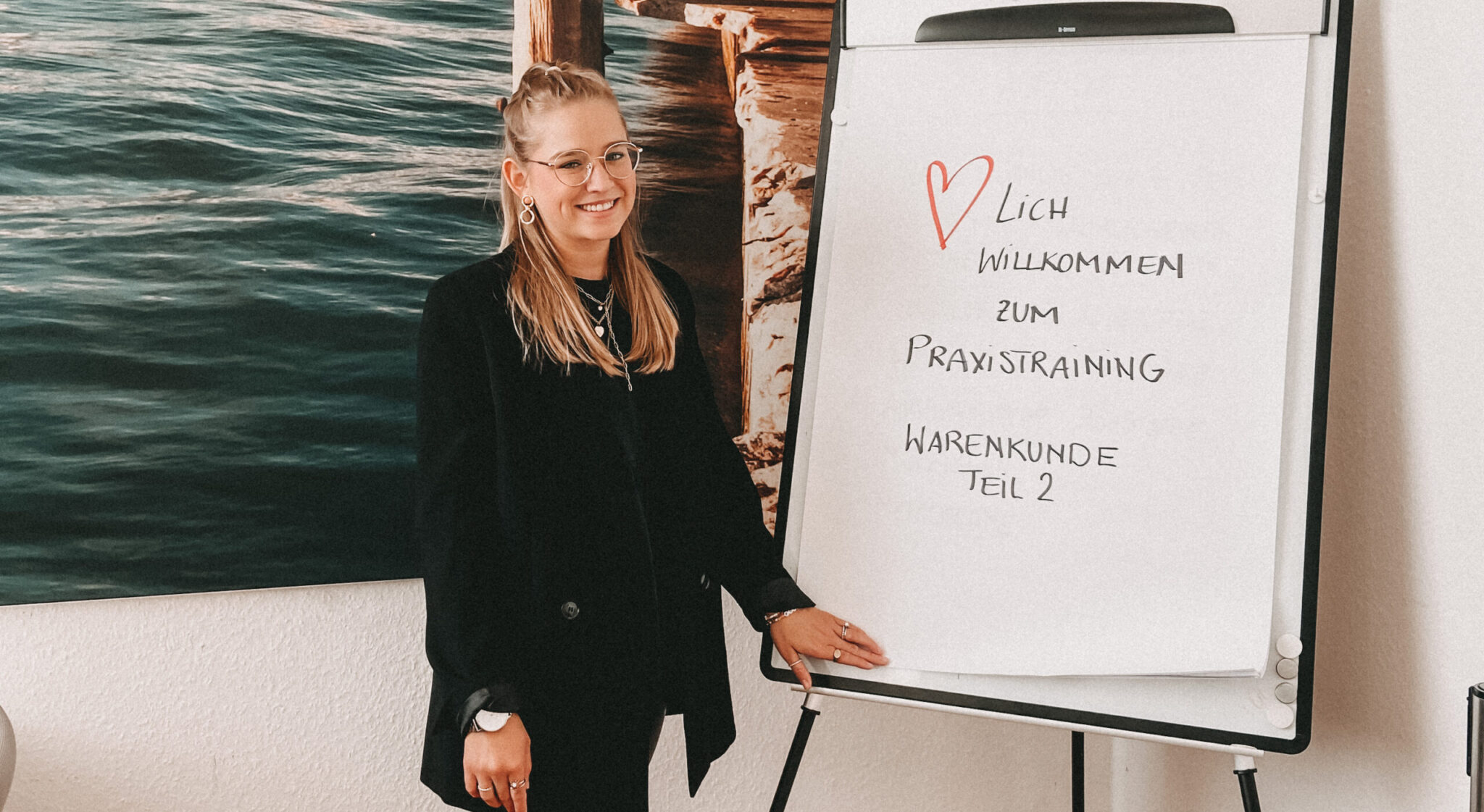 Ausbildungskoordinatorin Eva steht vor einem Flipchart für das Praxistraining und schaut in die Kamera.